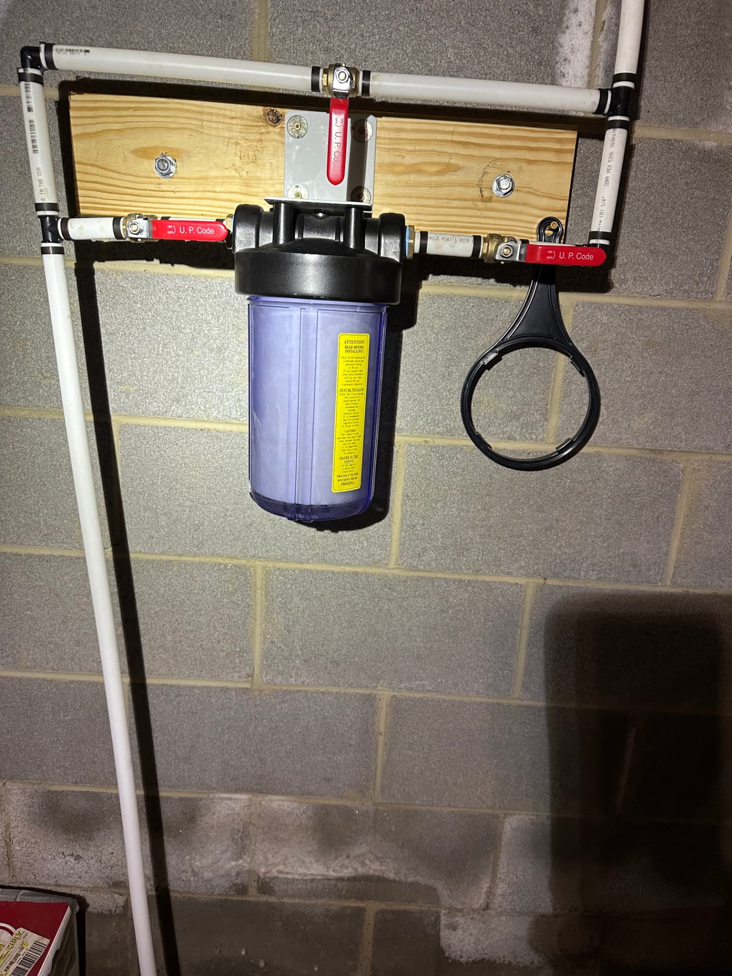 Whole-house filter housing mounted on a block basement wall