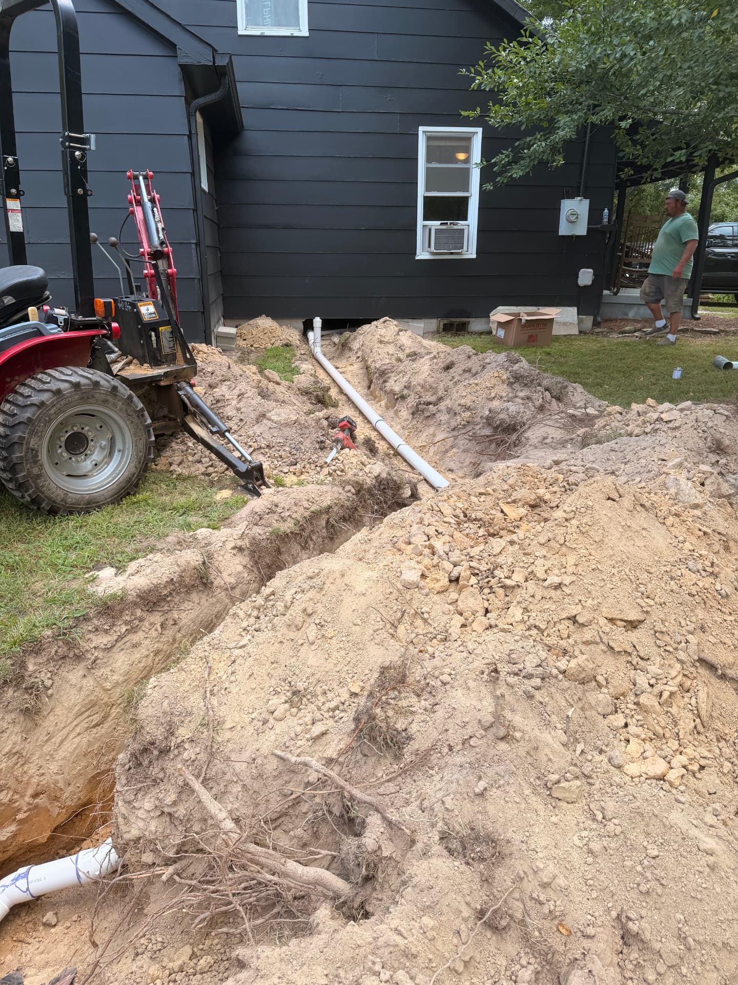 Sewer line excavation trench running alongside a home