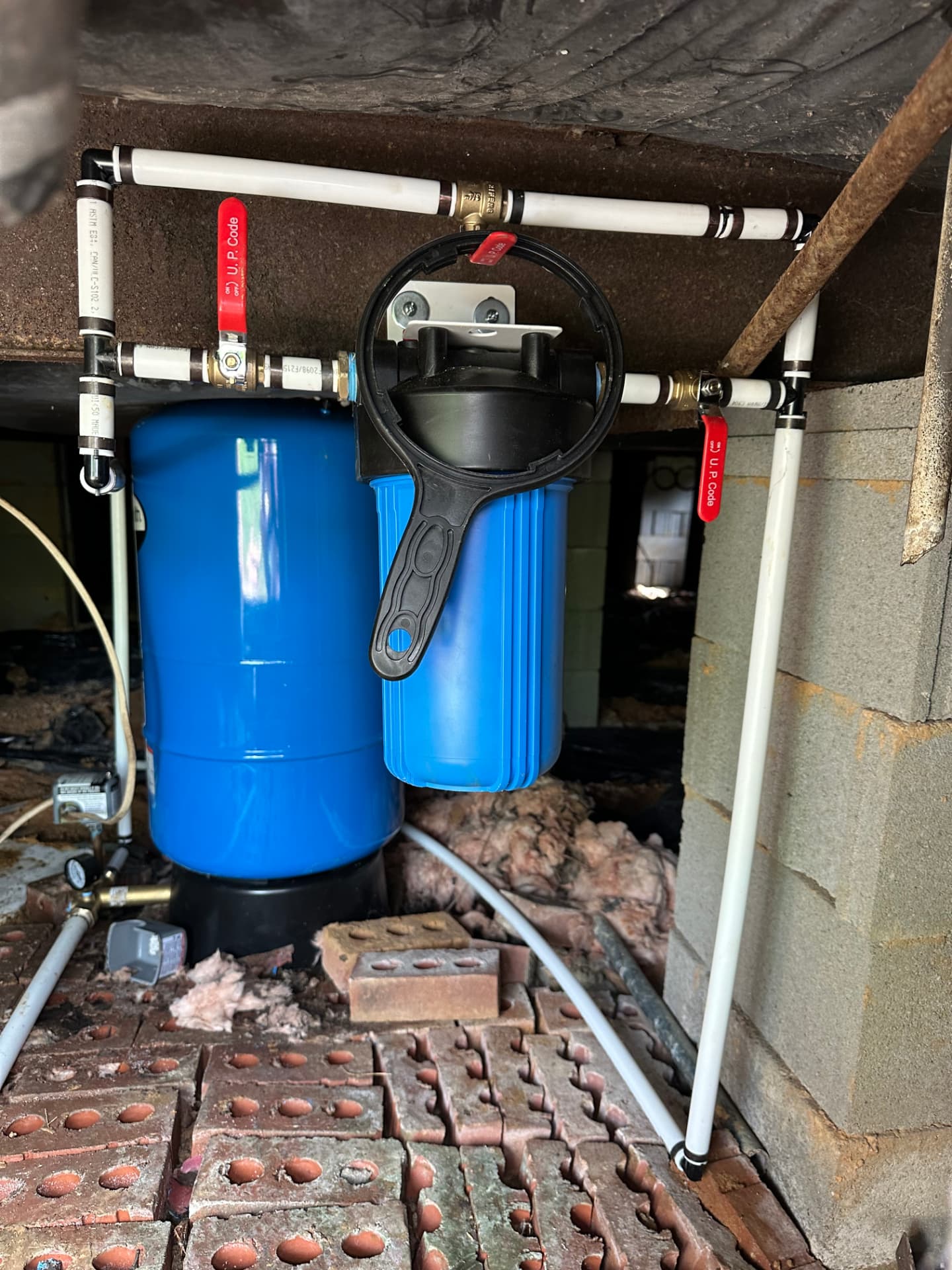 Whole-house filter and pressure tank plumbed in a crawlspace